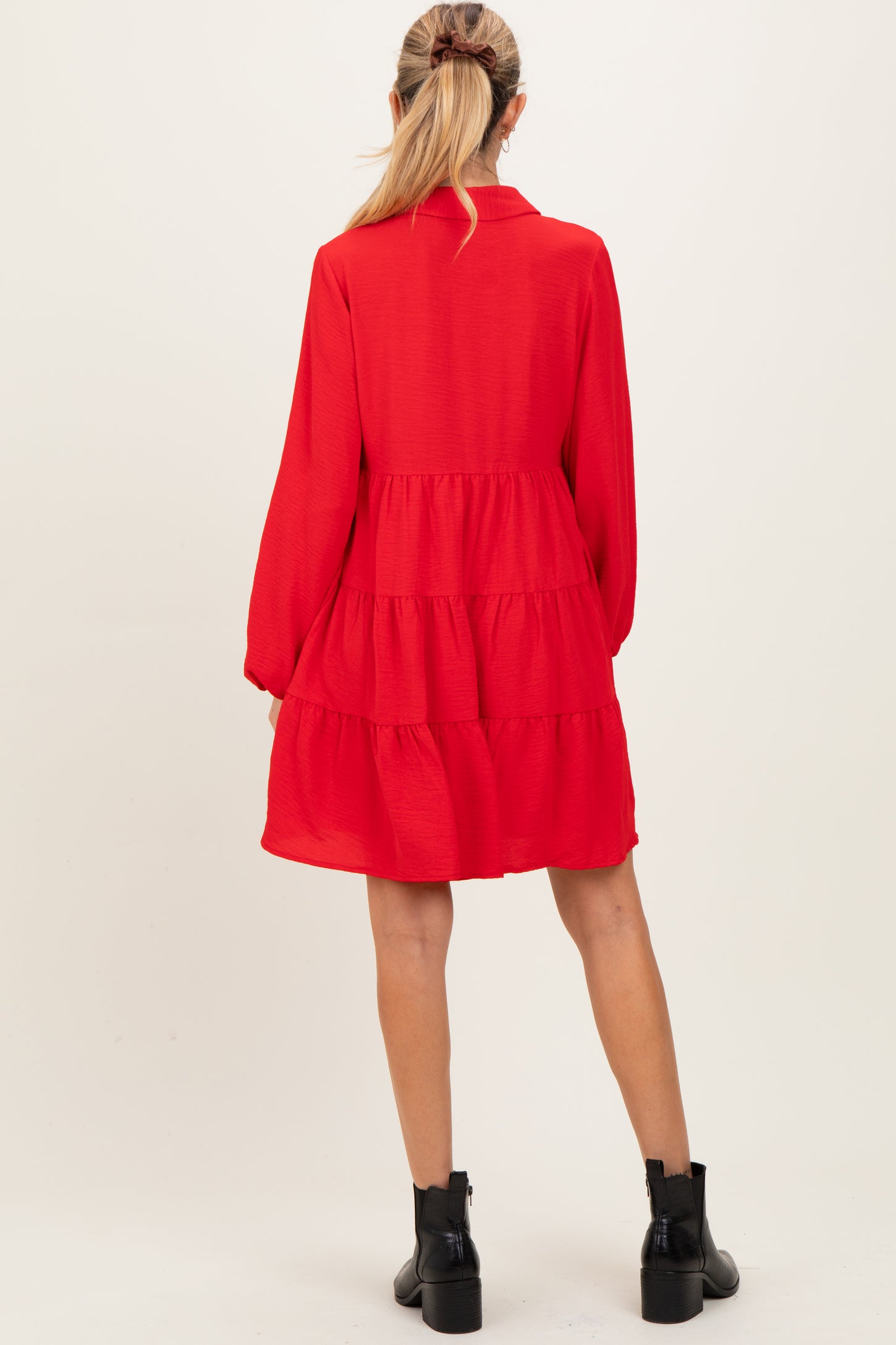 woman wearing a red tiered maternity dress with long sleeves and a collared neckline, back view