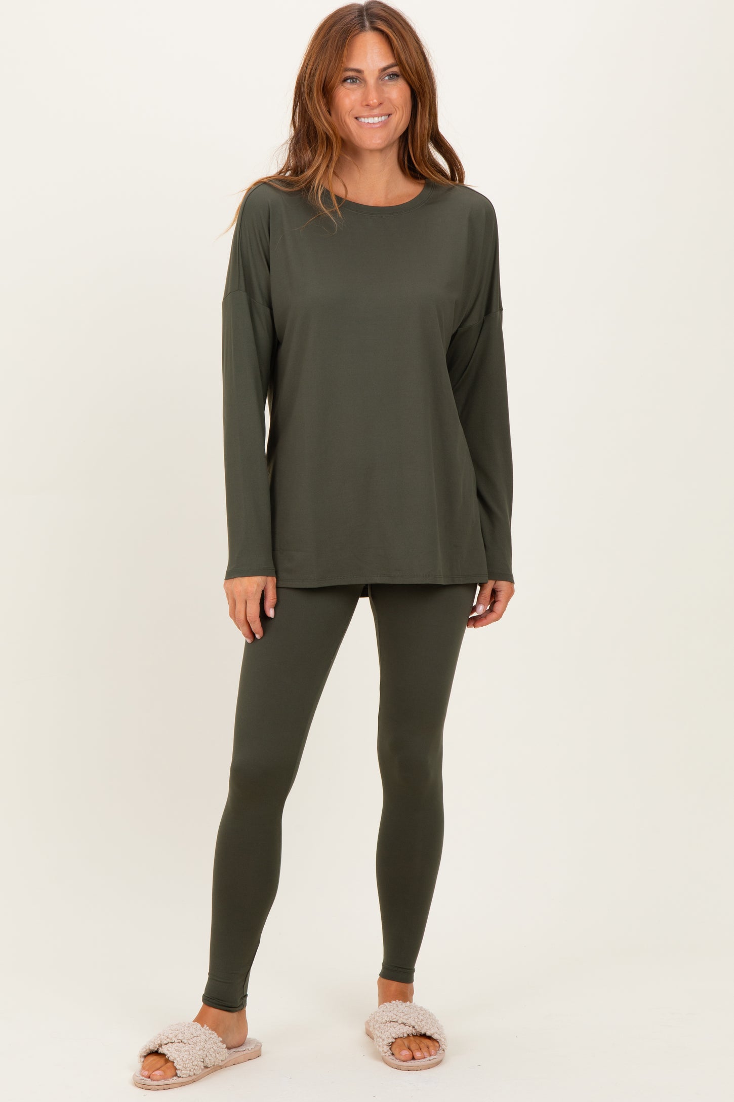 woman wearing an olive green long sleeve top and matching leggings, styled with cozy pink slipper sandals