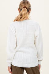 woman wearing a white knitted maternity sweater with dropped shoulders and a relaxed fit, showing the back view