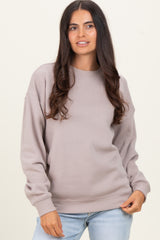 woman wearing a taupe long sleeve sweatshirt with a relaxed fit and ribbed cuffs, styled with light blue jeans