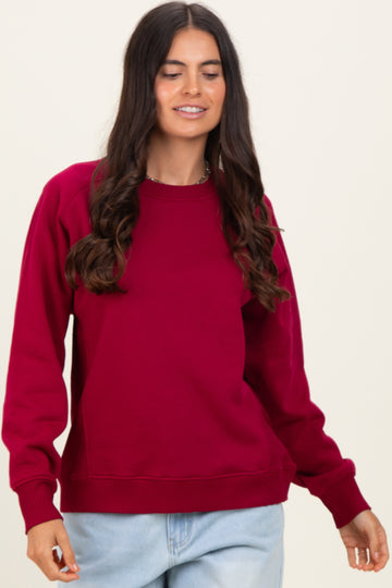 woman wearing a burgundy long sleeve sweatshirt with a relaxed fit and ribbed detailing on cuffs and hem