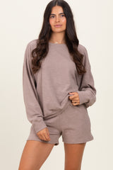 woman wearing a taupe oversized long sleeve sweatshirt and matching shorts