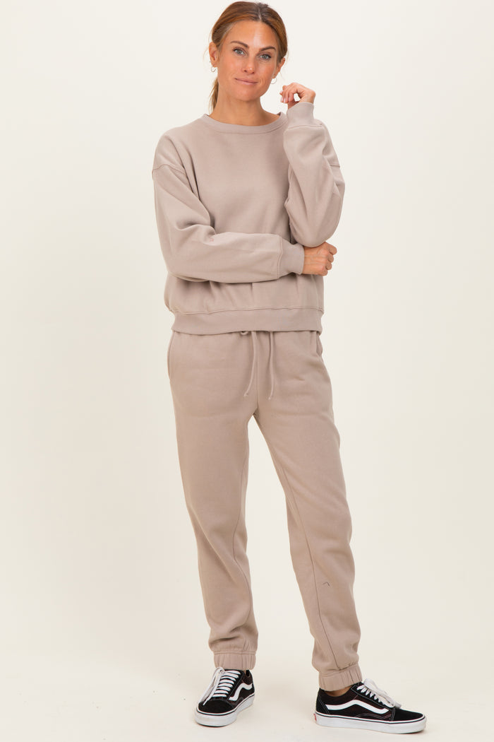 woman wearing a beige oversized sweatshirt and matching joggers, styled with black sneakers