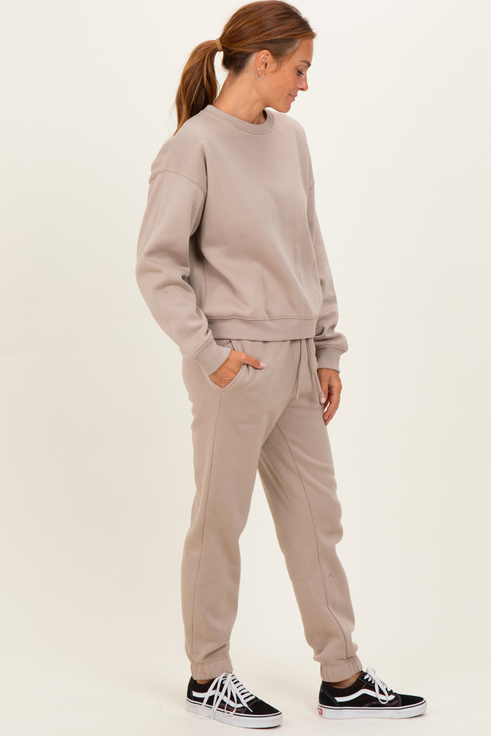 woman wearing a taupe oversized sweatshirt and matching joggers with side pockets and a relaxed fit