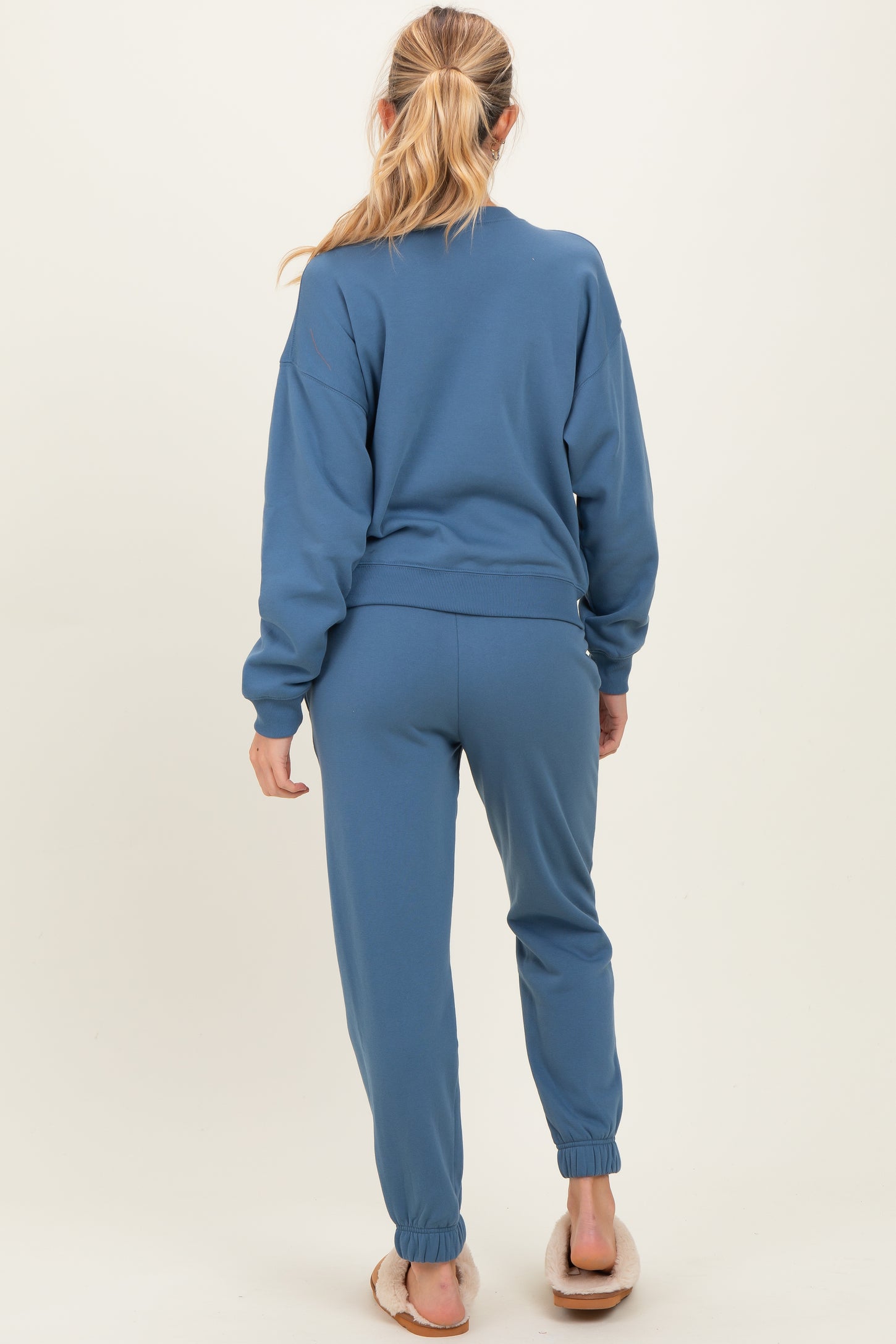 woman wearing a blue maternity sweatshirt and matching jogger pants, showing the back view with a relaxed fit