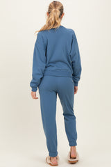 woman wearing a blue maternity sweatshirt and matching jogger pants, showing the back view with a relaxed fit
