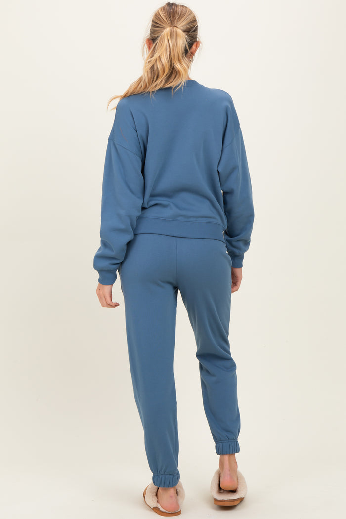 woman wearing a blue maternity sweatshirt and matching jogger pants, showing the back view with a relaxed fit
