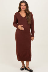 woman wearing a burgundy long sleeve maternity dress with a v-neck and holding her baby bump