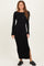 woman wearing a black ribbed long sleeve maxi dress with a side slit and black loafers