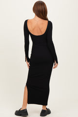 woman wearing a black long sleeve ribbed maxi dress with a deep back and side slit, standing against a neutral background