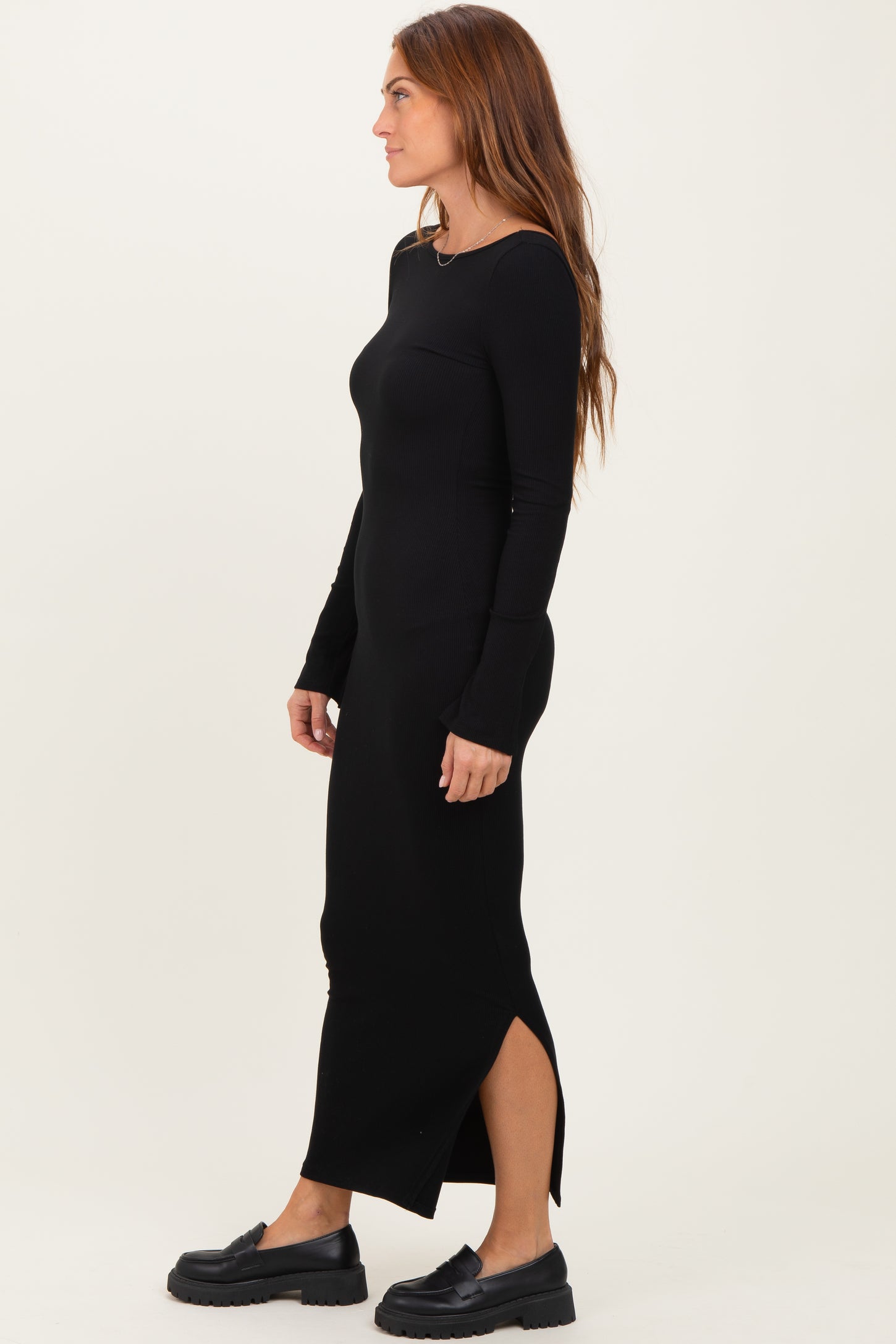 woman wearing a black long sleeve ribbed dress with side slits and chunky black platform shoes