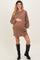 woman wearing a brown long sleeve maternity dress with pockets and holding her baby bump