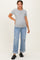 woman wearing a gray short sleeve maternity top and blue distressed jeans, showing off her baby bump