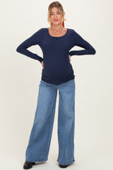 woman wearing a navy long sleeve maternity top and distressed wide leg jeans, showing her baby bump