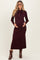 woman wearing a burgundy ribbed maternity dress with a bow tie detail and holding her baby bump