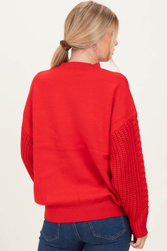 woman wearing a red oversized sweater with knitted sleeves, viewed from the back
