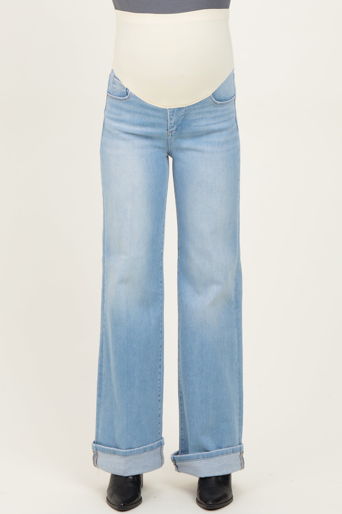 woman wearing light blue flared maternity jeans with a stretchy belly band, slightly rolled cuffs at the ankles