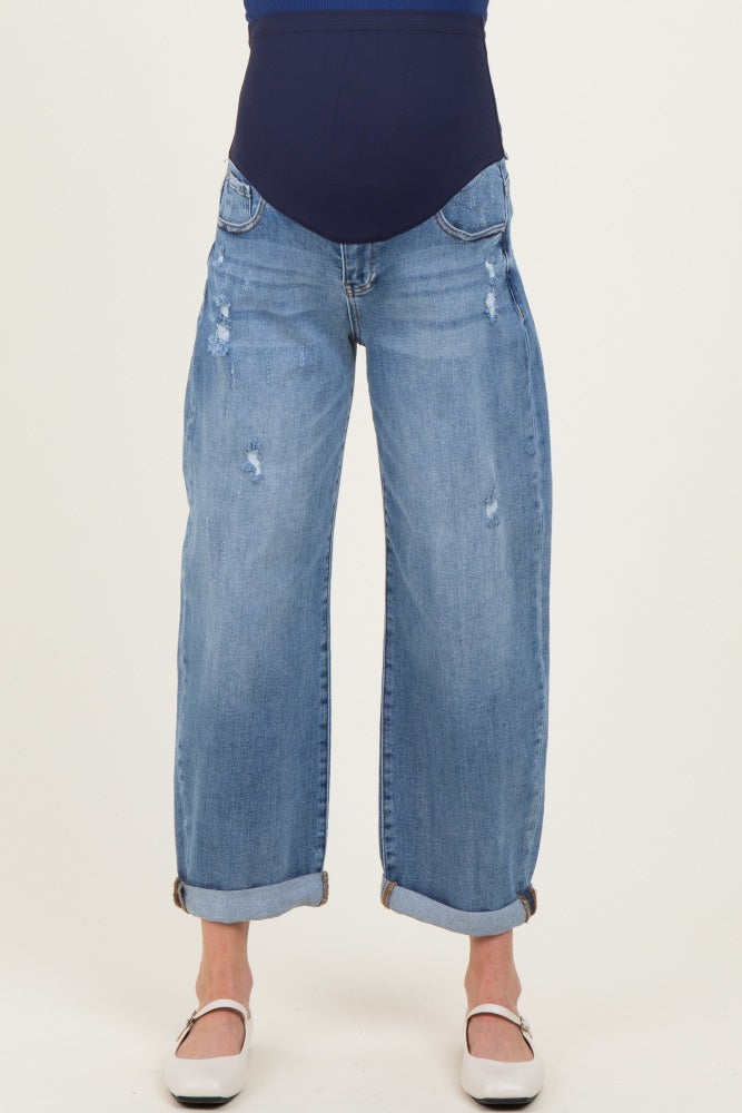 woman wearing a pair of light blue distressed maternity jeans with a wide leg and cuffed hem