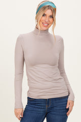 woman wearing a beige long sleeve turtleneck top with a fitted style and light blue and green striped headband