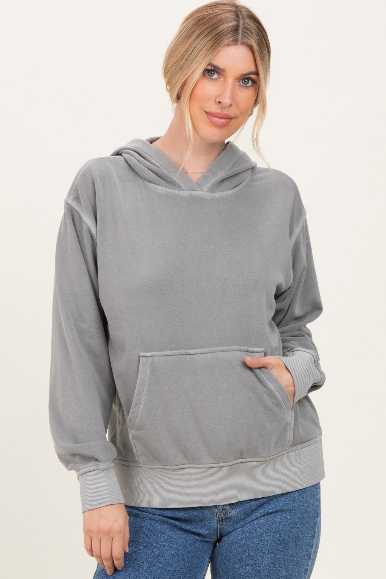 woman wearing a gray pullover hoodie with a front pocket and hood, styled with jeans