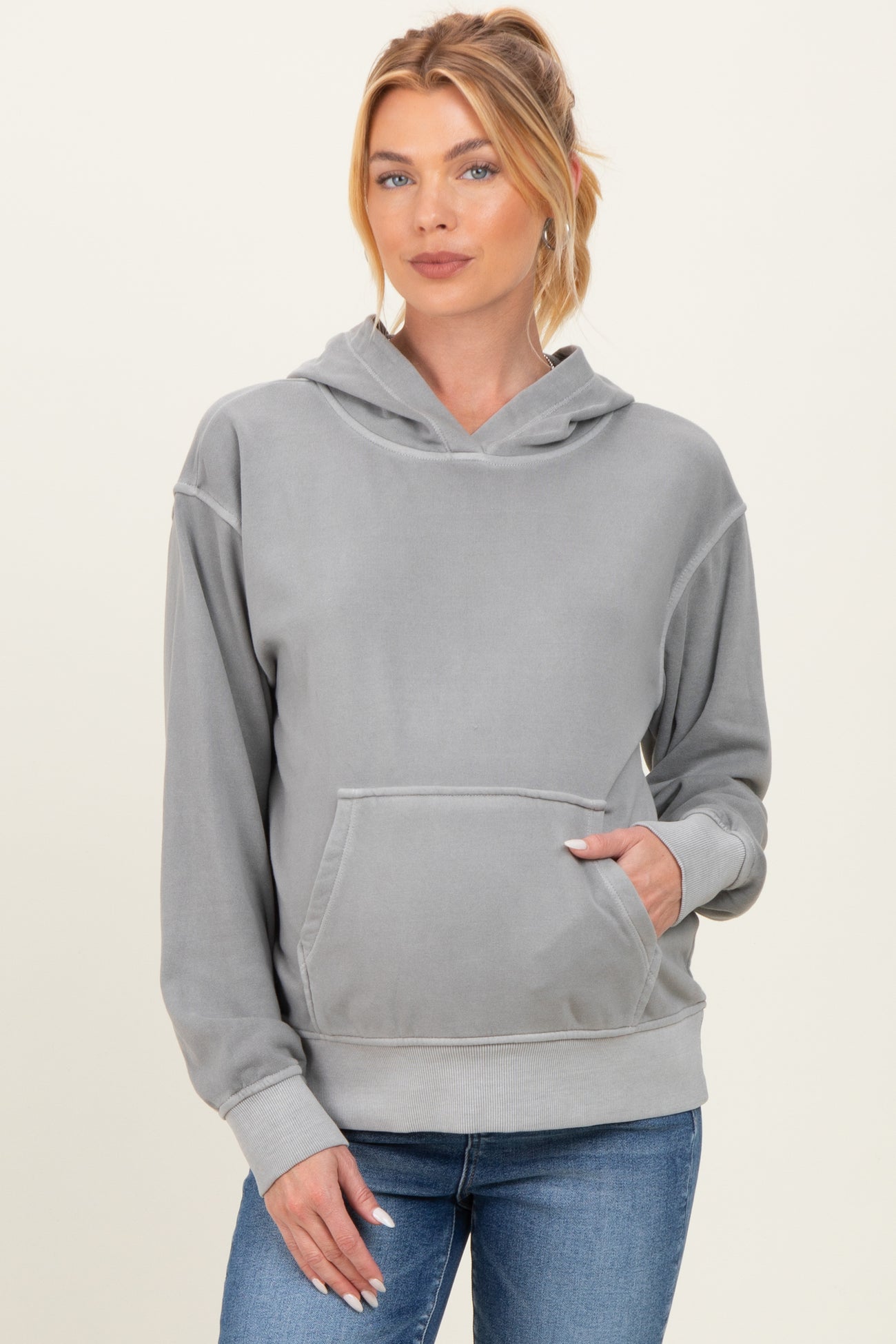 woman wearing a gray maternity hoodie with a front pocket and a hood, paired with jeans