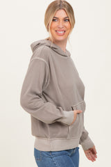 woman wearing a taupe oversized hoodie with a front pocket and side view, paired with blue jeans