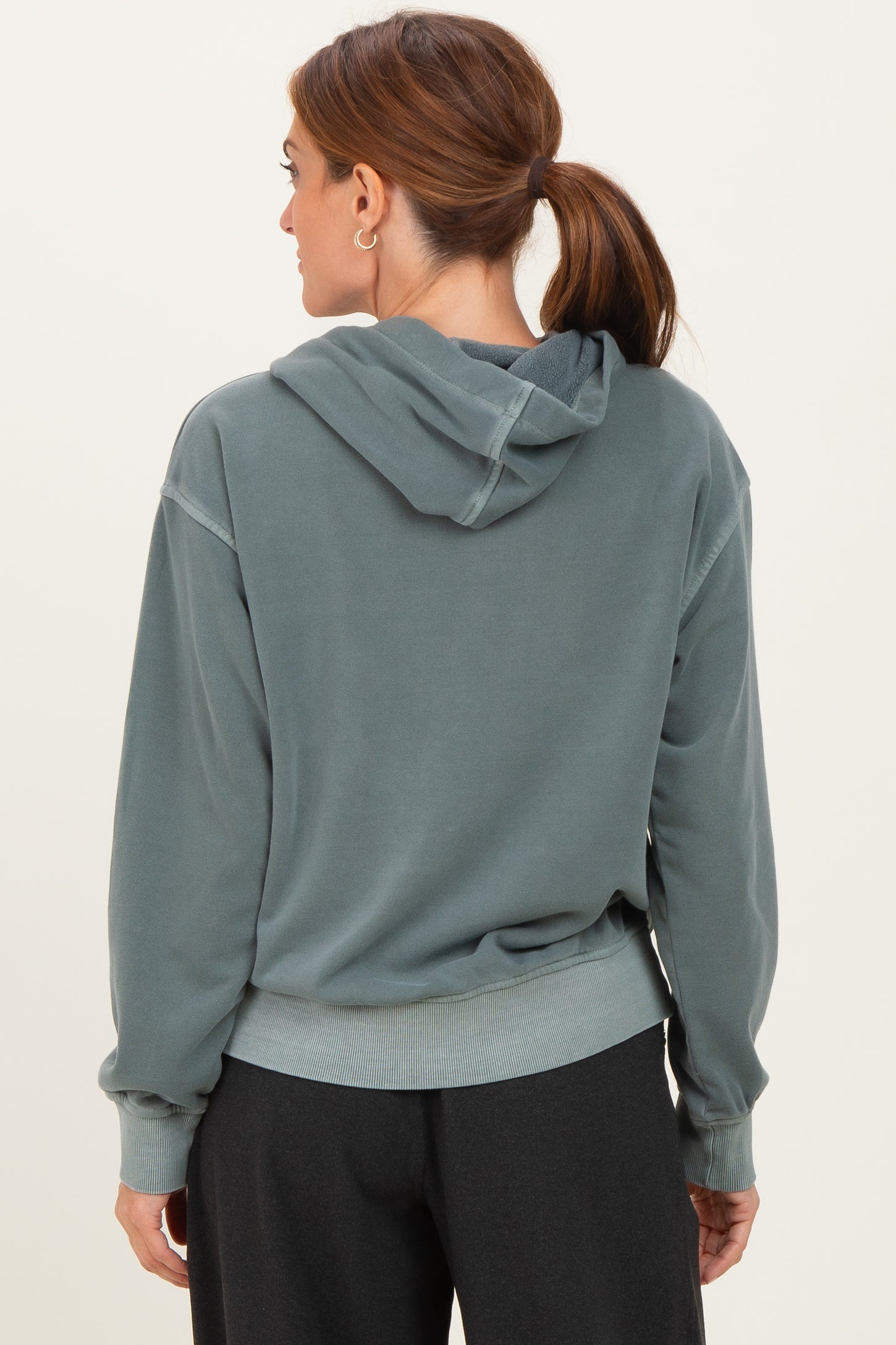 woman wearing a gray hooded sweatshirt with a relaxed fit and ribbed cuffs, viewed from the back