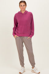 woman wearing a fuchsia oversized hoodie with a front pocket and gray ribbed jogger pants