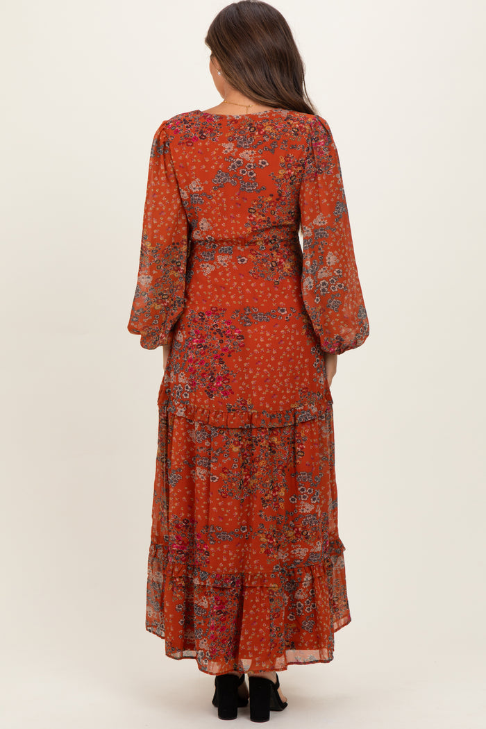 woman wearing a rust floral long sleeve maternity maxi dress with tiered ruffles, shown from the back.