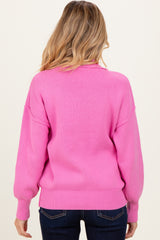 woman wearing a bright pink oversized maternity sweater shown from the back