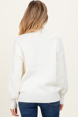 woman wearing a white oversized maternity sweater, showing the back view with relaxed fit and ribbed details