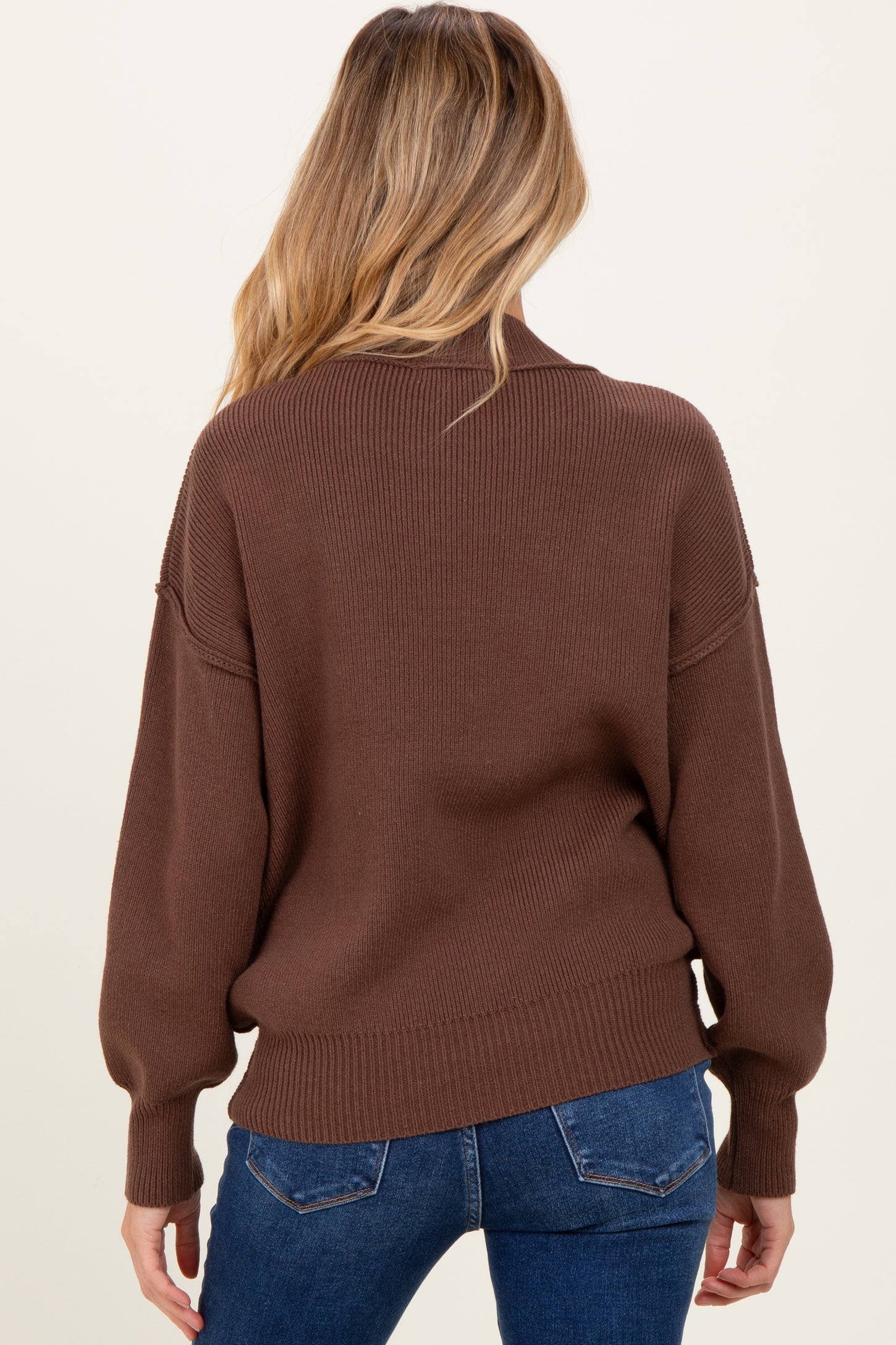 woman wearing a brown oversized knitted maternity sweater with a relaxed fit and long sleeves