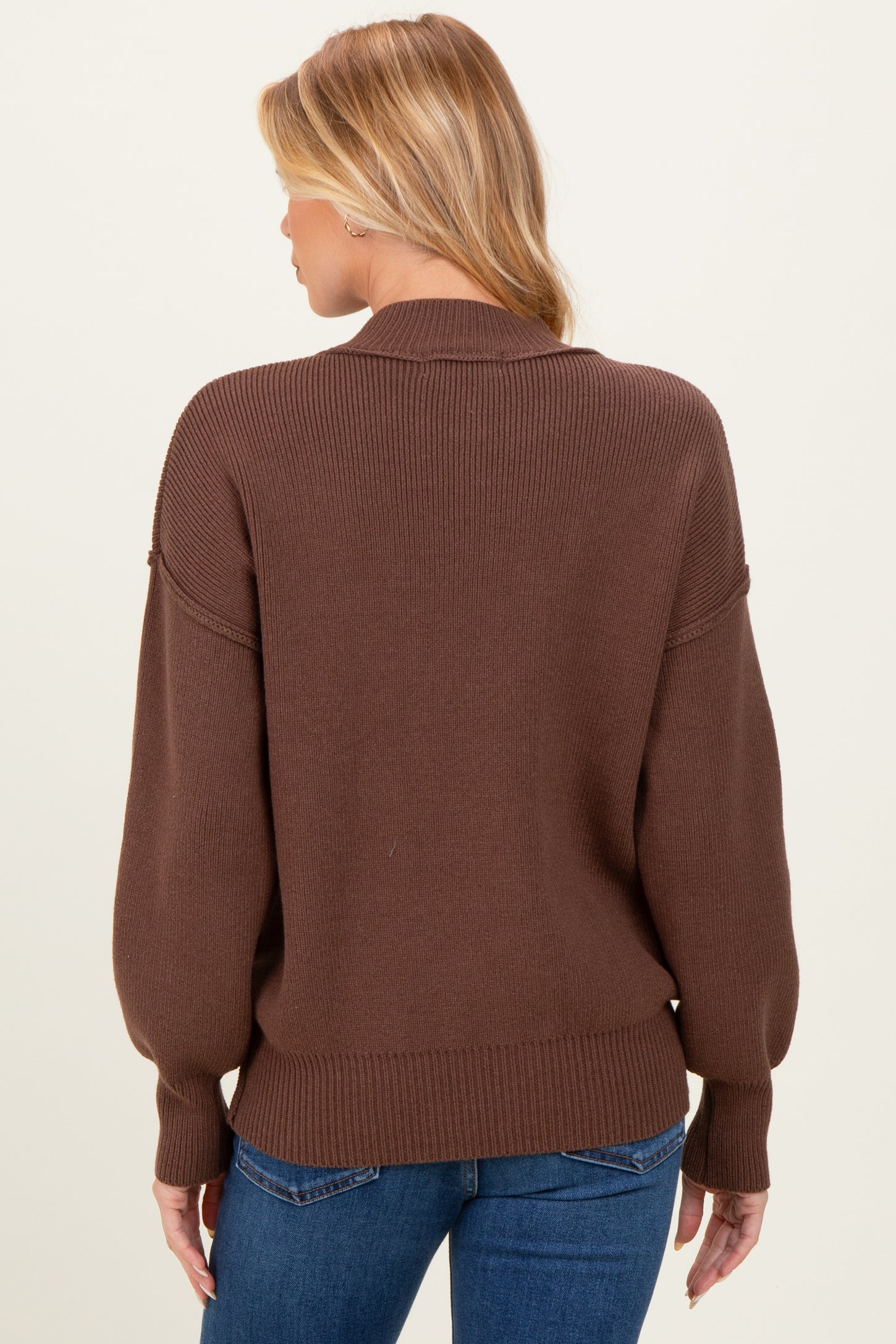 woman wearing a brown maternity sweater with a relaxed fit and oversized sleeves, viewed from the back