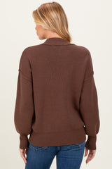 woman wearing a brown maternity sweater with a relaxed fit and oversized sleeves, viewed from the back