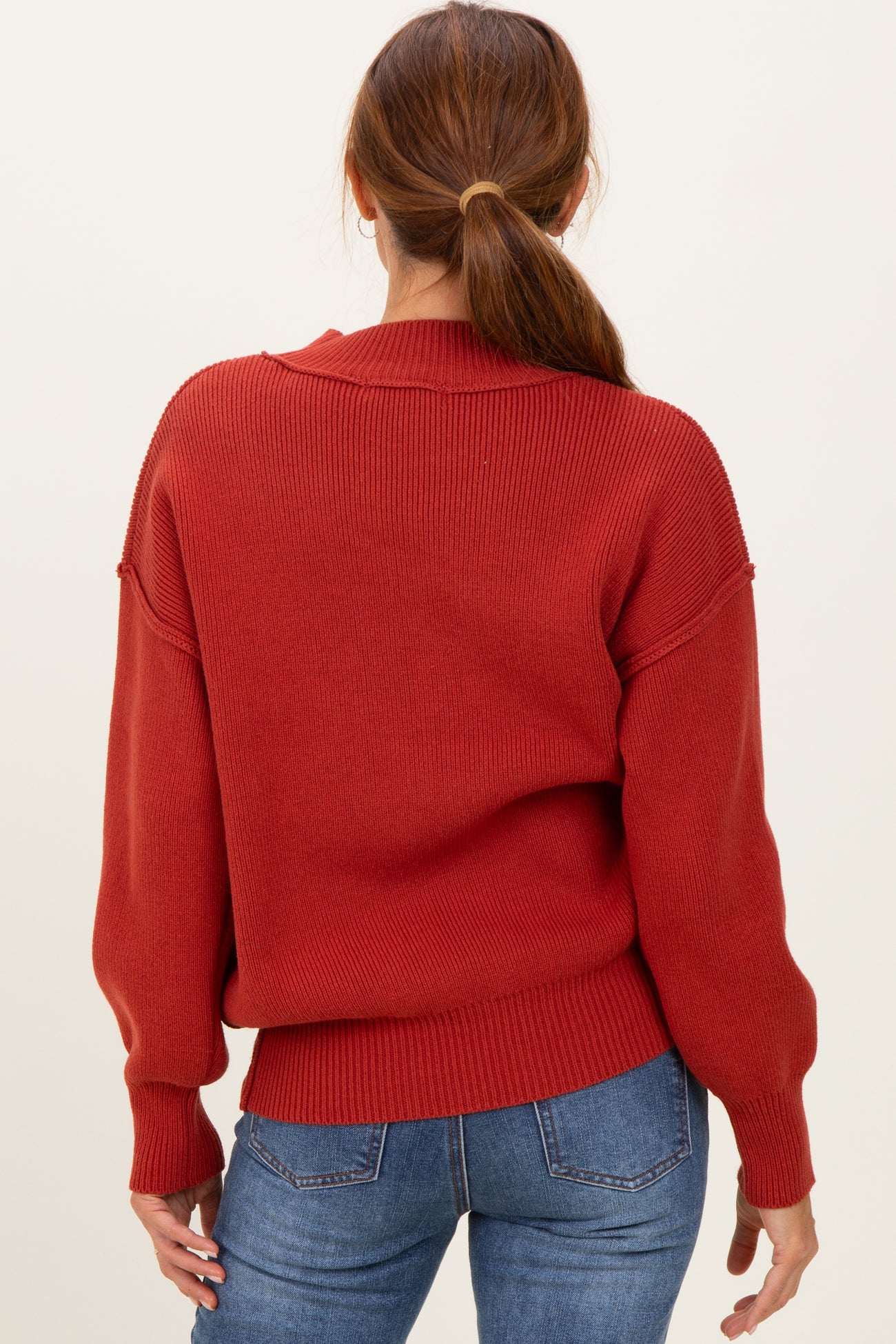 woman wearing a cozy red oversized sweater with long sleeves, styled with a relaxed fit and ribbed details