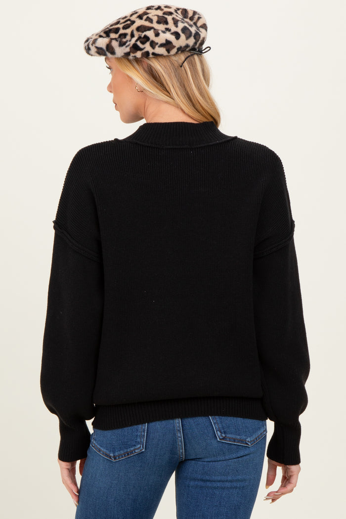 woman wearing a black maternity sweater with balloon sleeves and a high neck, seen from the back