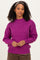 woman wearing a fuchsia oversized ribbed sweater with a high neck and long sleeves