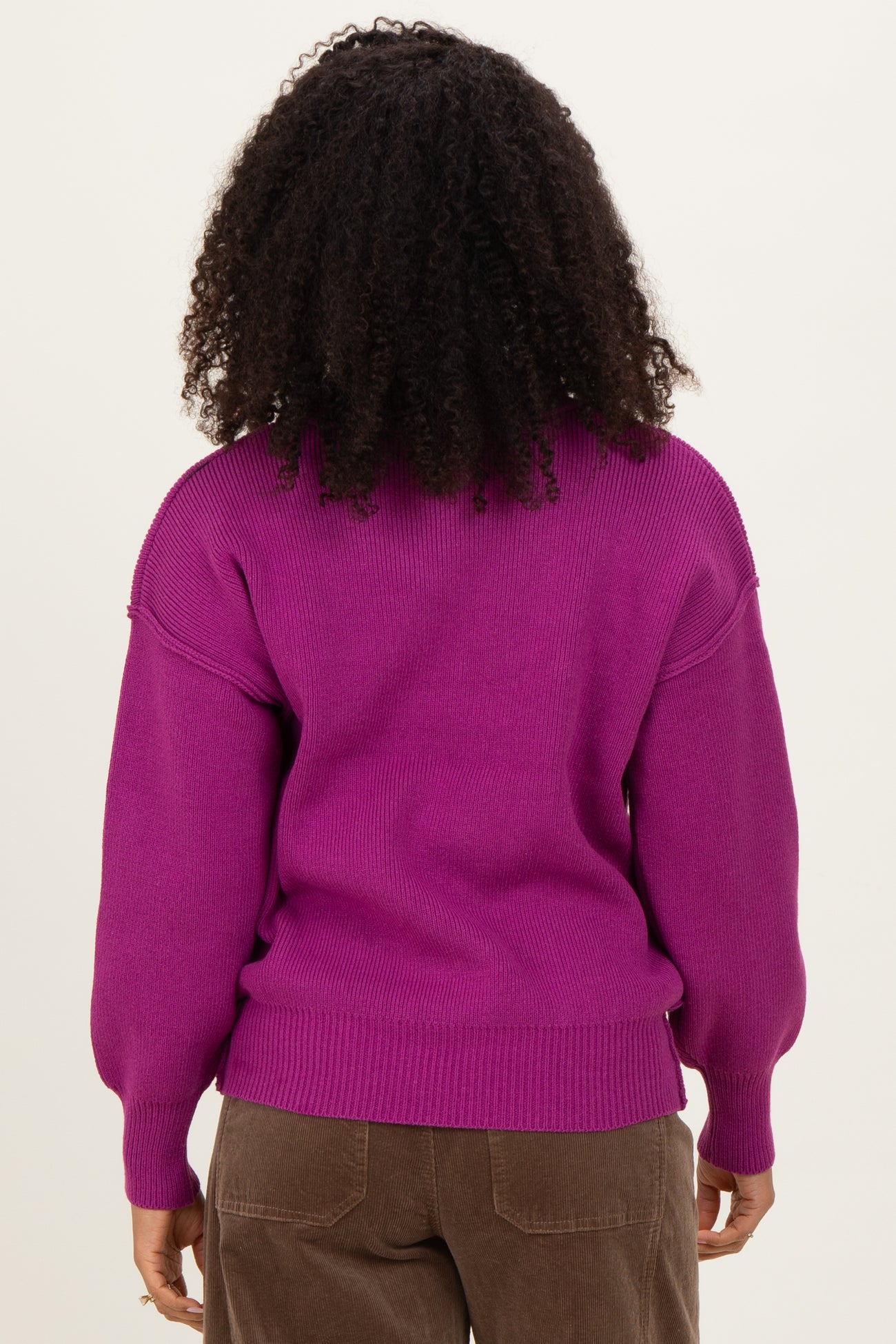 woman wearing a bright purple oversized sweater with puffed sleeves and ribbed hem, showing the back view