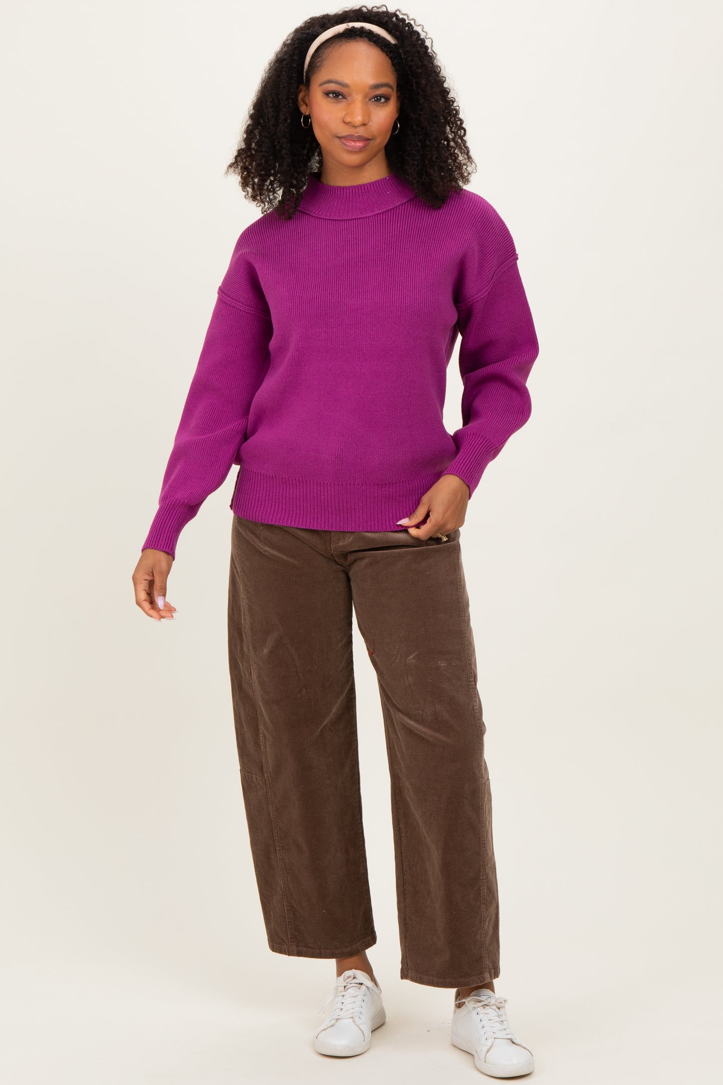 woman wearing a vibrant purple knit sweater and brown wide-leg corduroy pants with white sneakers