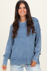 woman wearing a blue ribbed oversized sweater with a high neckline and side slits