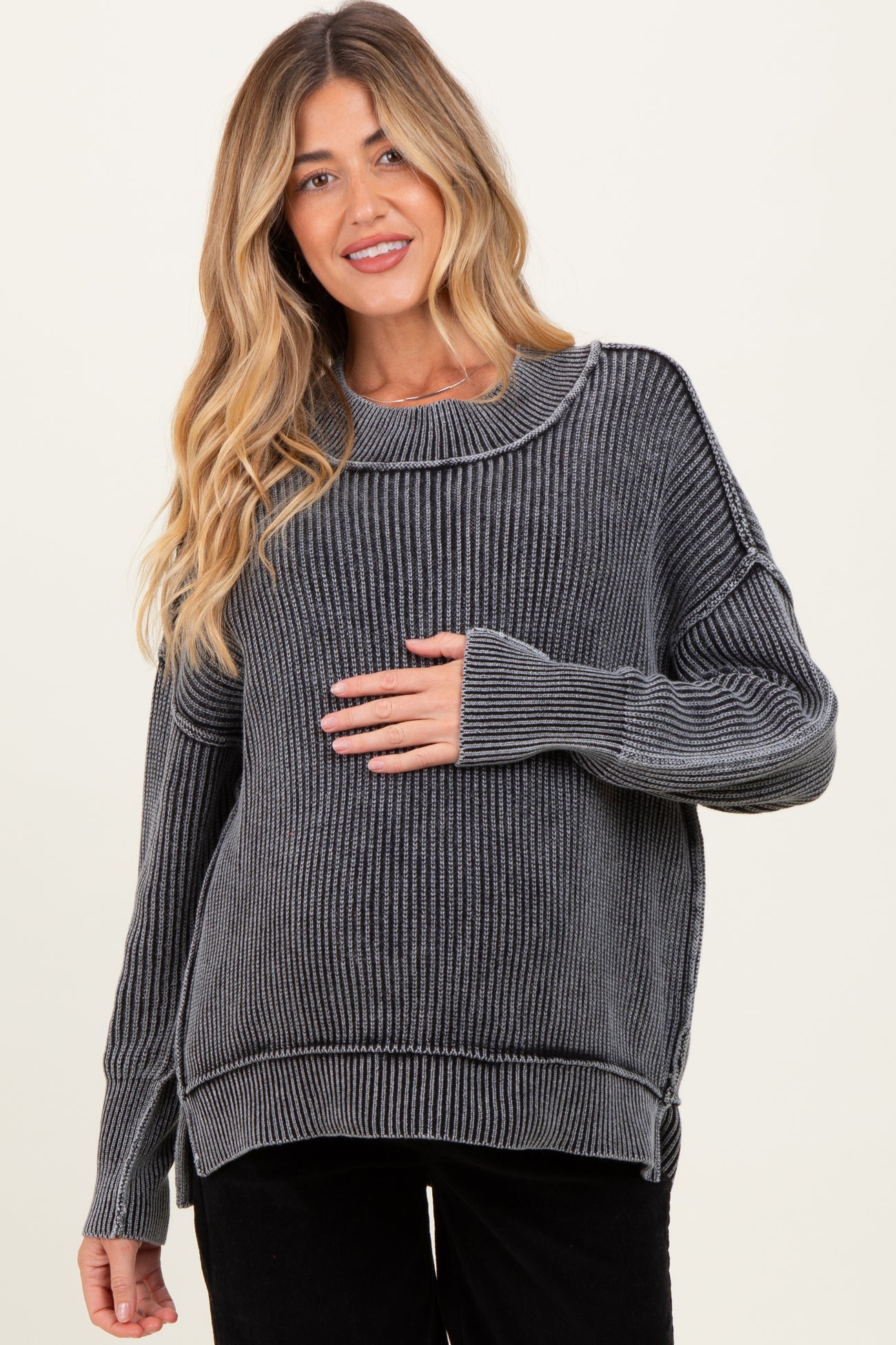 woman wearing a gray striped maternity sweater and holding her baby bump