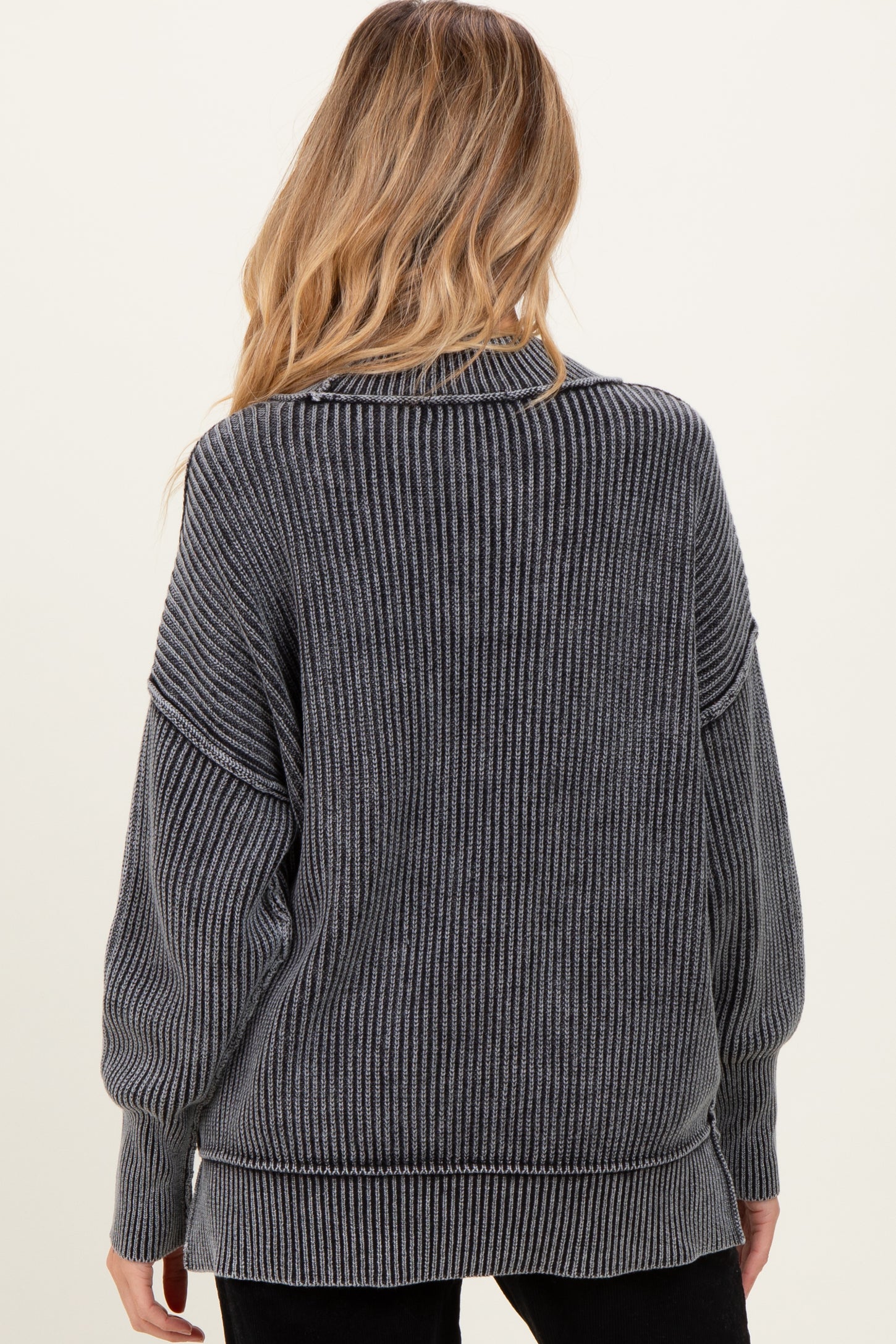 woman wearing a dark gray maternity sweater with ribbed texture and oversized fit, seen from the back