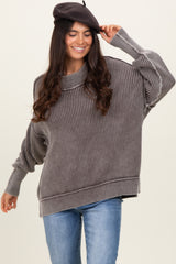 woman wearing a cozy gray striped oversized sweater with a high neckline and relaxed sleeves, smiling and posing with a beret