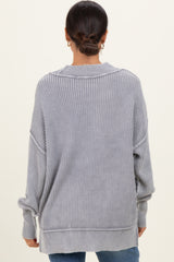 woman wearing a light gray oversized ribbed sweater with dropped shoulders and side slits, viewed from the back