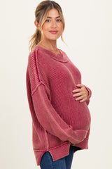 woman wearing a raspberry ribbed maternity sweater and holding her baby bump