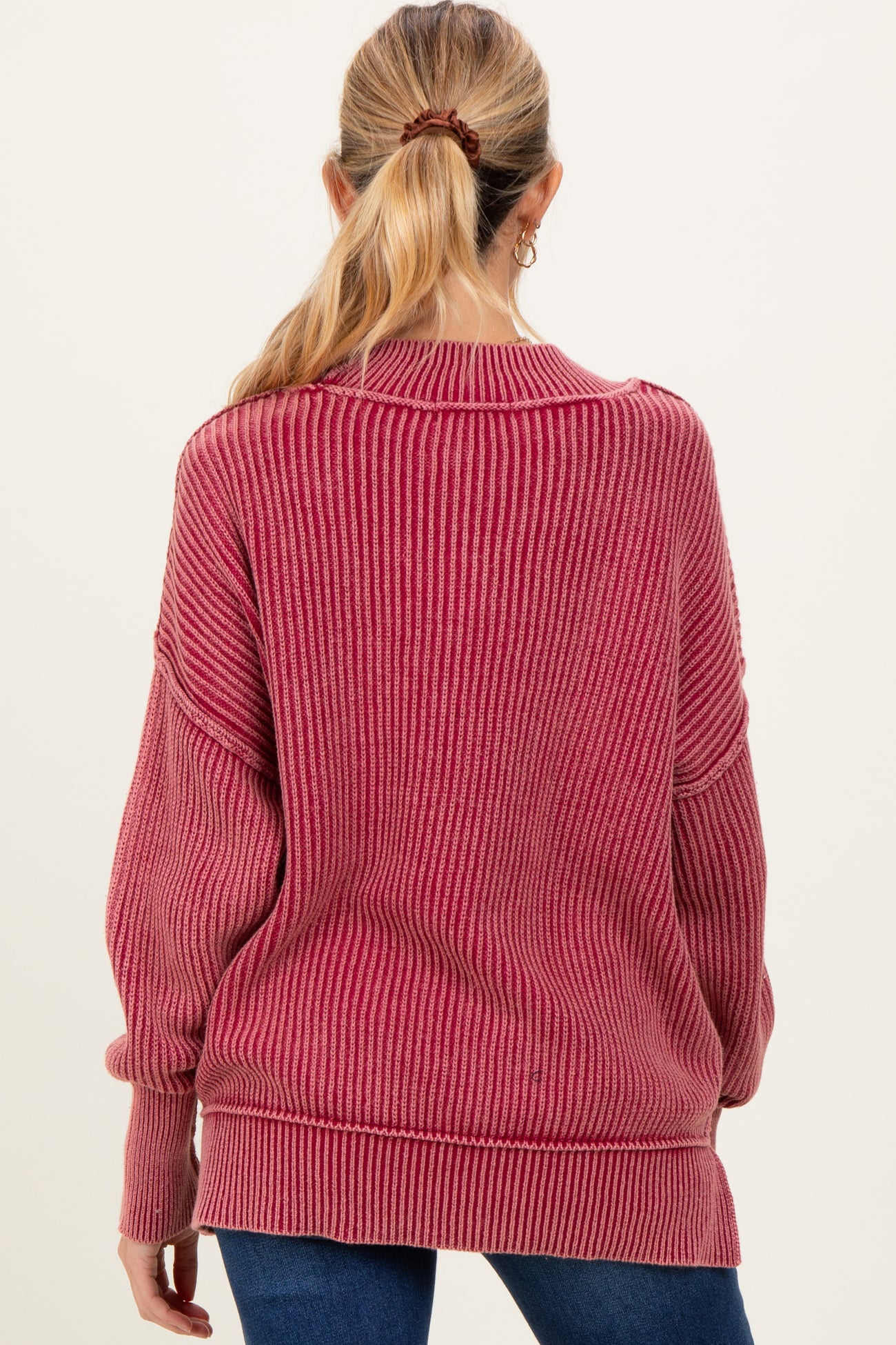 woman wearing a burgundy striped oversized maternity sweater viewed from the back