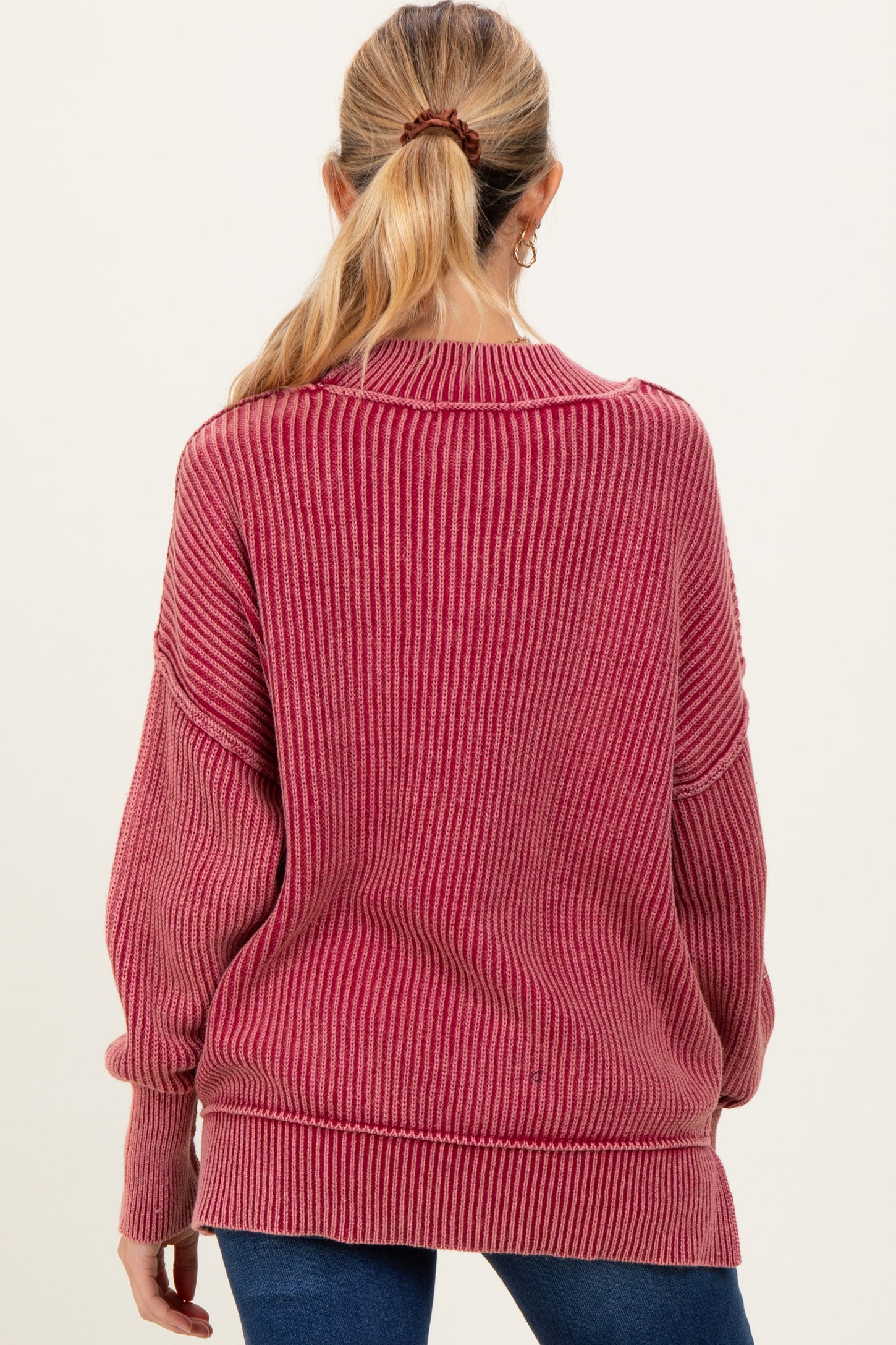 woman wearing a burgundy striped oversized maternity sweater viewed from the back