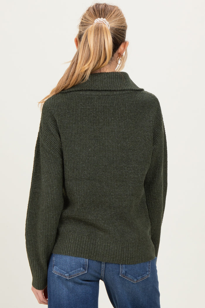 woman wearing a dark green oversized maternity sweater with a ribbed texture, showing the back view