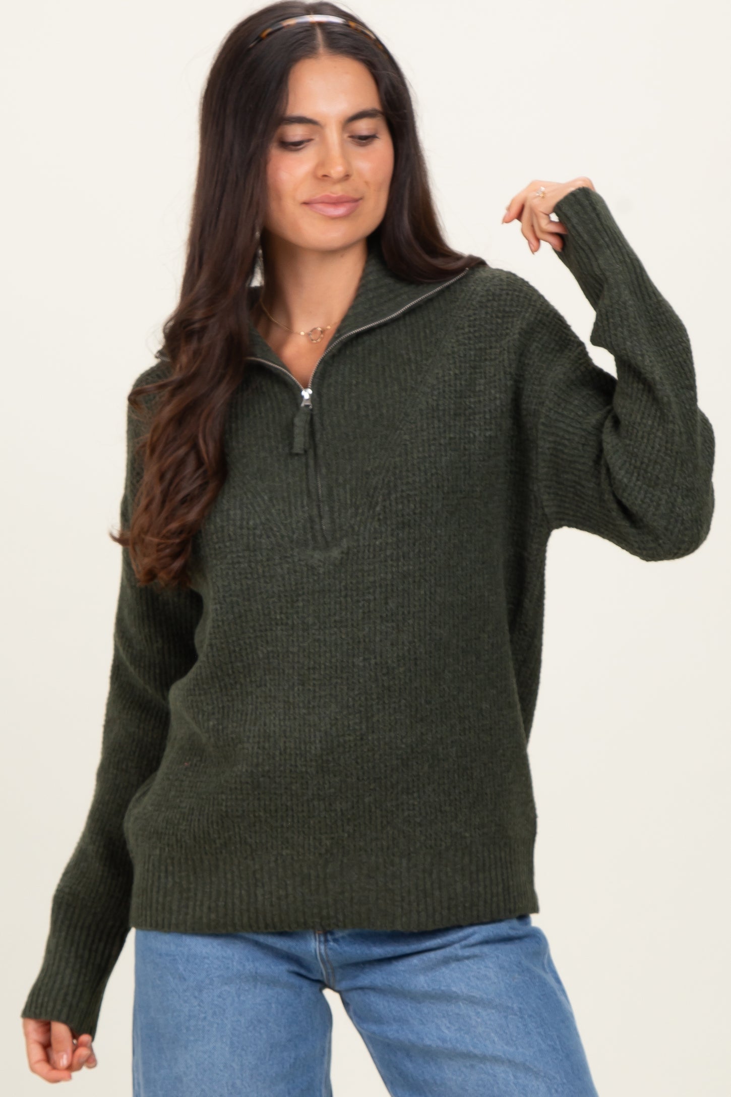 woman wearing a dark green zip-up knit sweater with long sleeves and a relaxed fit