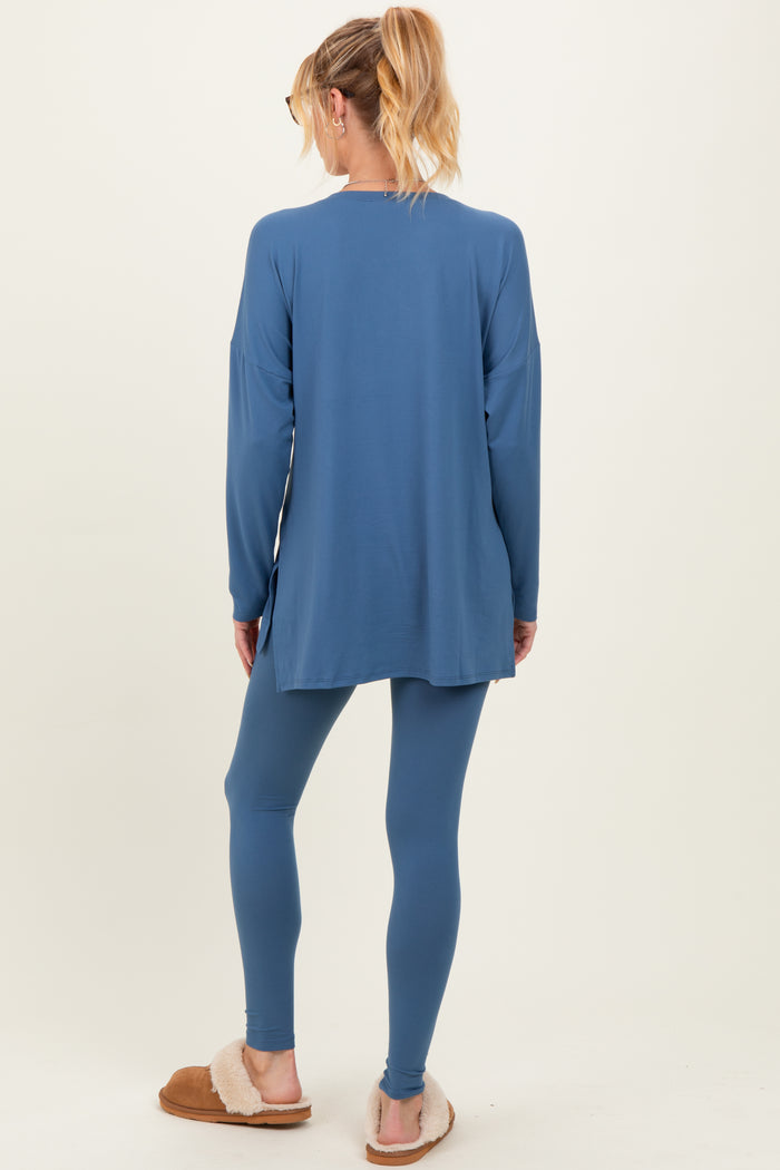 woman wearing a blue maternity tunic and leggings, standing with her back to the camera, showing a relaxed fit